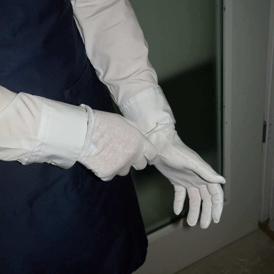 A Ketterer Kunst staff member puts on white gloves before handling a work